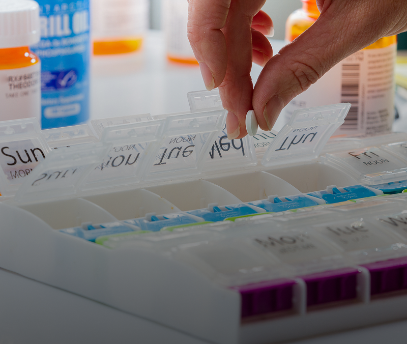 Hand organizing weekly pill organizer.